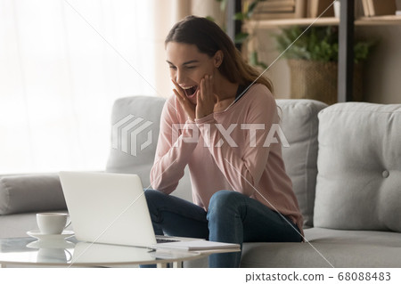 Amazed girl feeling great surprise looking at laptop at home 68088483