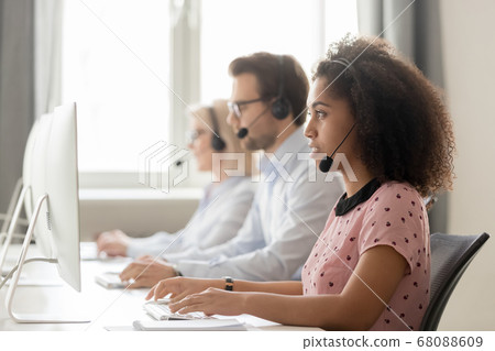 Focused african call center operator consulting customer looking at computer 68088609