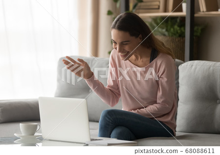 Happy young woman waving hand making video call on laptop Happy young woman waving hand making video call on laptop 68088611