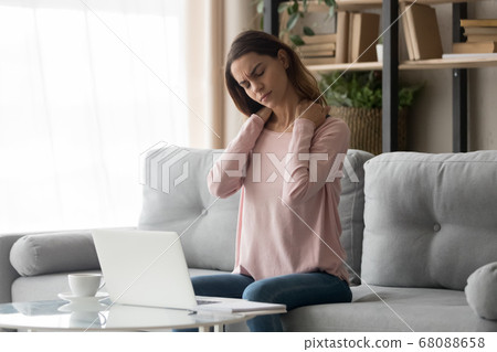Tired woman feeling neck pain after computer work at home Tired woman feeling neck pain after computer work at home 68088658