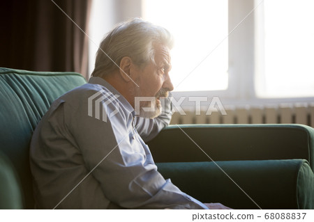 Thoughtful senior grandpa sit alone on sofa thinking of loneliness Thoughtful senior grandpa sit alone on sofa thinking of loneliness 68088837