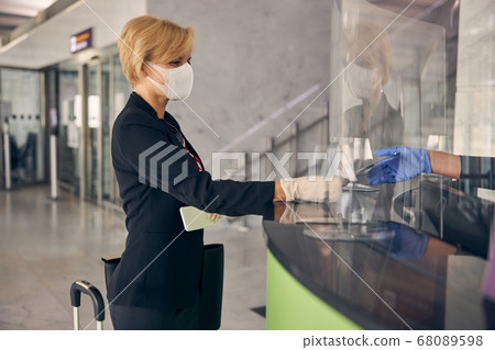 Charming businesswoman showing ticket at check-in desk in airport 68089598