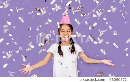 Joyful Birthday Girl Standing Under Falling Confetti, Purple Background Joyful Birthday Girl Standing Under Falling Confetti, Purple Background 68090272