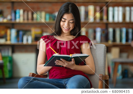 Asian student girl sitting in library and taking notes to notepad 68090435