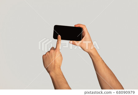 Unrecognizable millennial man touching screen of cellphone over light background, space for mobile app design Unrecognizable millennial man touching screen of cellphone over light background, space for mobile app design 68090979