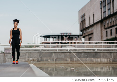 Beautiful athletic sportswoman on street. African american girl with closed eyes, in sportswear, with fitness tracker Beautiful athletic sportswoman on street. African american girl with closed eyes, in sportswear, with fitness tracker 68091279