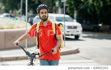 Delivery to home or office. Young man in protective helmet with backpack with bicycle looking for the address of client 68091301