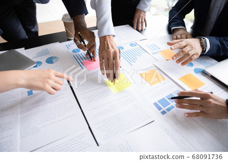 Closeup view diverse businesspeople discuss paperwork data statistics at meeting Closeup view diverse businesspeople discuss paperwork data statistics at meeting 68091736