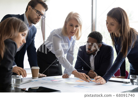 Mature leader with young teammates discuss financial report at meeting Mature leader with young teammates discuss financial report at meeting 68091740
