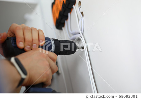 Man holds hammer drill in his hands and drills hole. 68092391