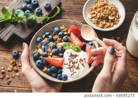 Eating granola with greek yogurt and berries Eating granola with greek yogurt and berries 68095273