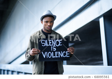 Man with silence is violence sign standing outdoors, black lives matter concept. 68095561