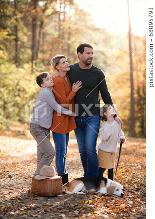 Beautiful young family with small children and dog standing in autumn forest. Beautiful young family with small children and dog standing in autumn forest. 68095791