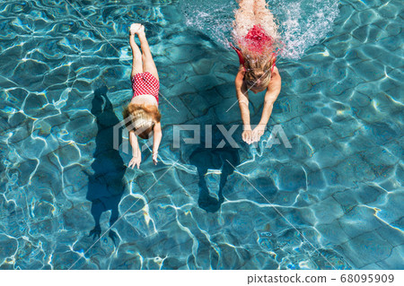 Child with mother dive underwater in swimming pool 68095909