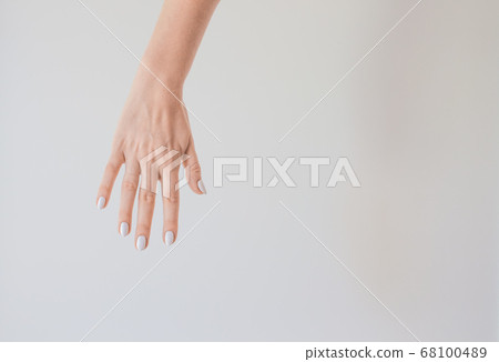 Female hand with a beautiful manicure on a background of a white wall. Delicate and healthy skin on the hands, rejuvenation of the skin of the hands, moisturizing and care Female hand with a beautiful manicure on a background of a white wall. Delicate and healthy skin on the hands, rejuvenation of the skin of the hands, moisturizing and care 68100489