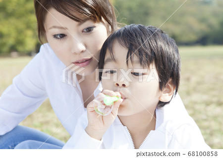Mother and child playing with soap bubbles 68100858