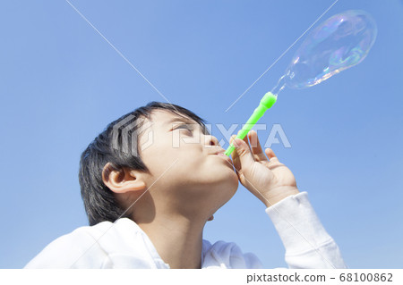 Boy blowing soap bubble 68100862