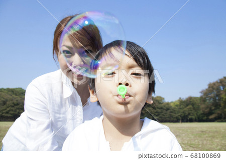 Mother and child playing with soap bubbles 68100869