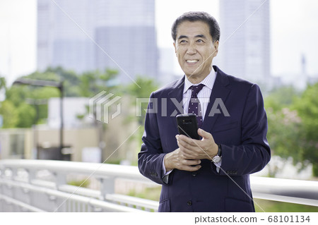 Senior businessman using a smartphone outdoors 68101134