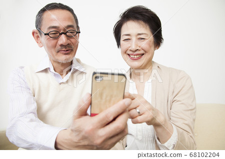 Senior couple looking at smartphones Senior couple looking at smartphones 68102204