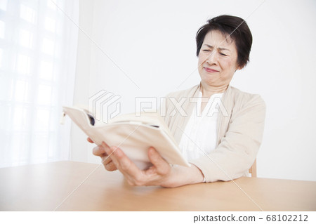 Senior woman reading a book with presbyopia 68102212