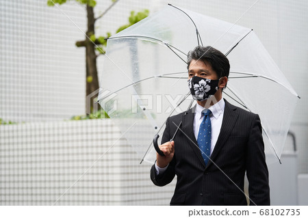 通勤的中間商人在雨中戴面具時在雨中與乙烯基傘一起使用 通勤的中間商人在雨中戴面具時在雨中與乙烯基傘一起使用 68102735
