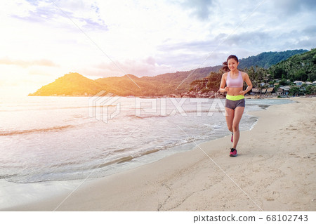 Runner woman running on beach in sunrise 68102743