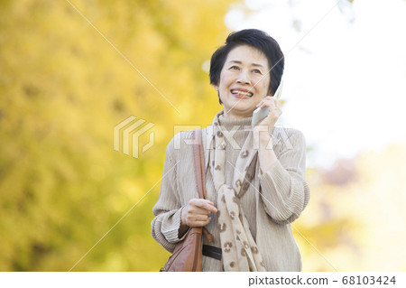 Senior woman calling outdoors 68103424
