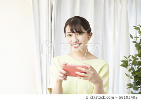 A woman listening to music on a smartphone A woman listening to music on a smartphone 68103492