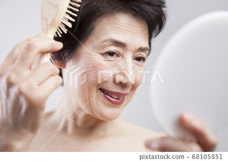 Senior woman combing hair Senior woman combing hair 68105851