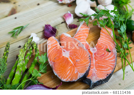Salmon steaks with fresh vegetables and mushrooms on wooden background Salmon steaks with fresh vegetables and mushrooms on wooden background 68111436