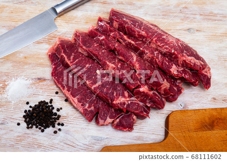Sliced raw veal steak on wooden table 68111602