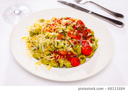 Spinach tortellini served with tomato sauce and greens Spinach tortellini served with tomato sauce and greens 68111884