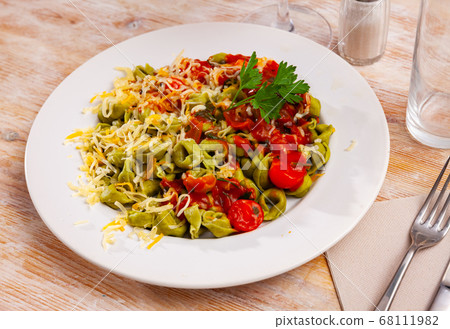 Spinach tortellini served with tomato sauce and greens 68111982