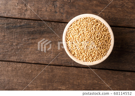 White mustard seeds in bowl on wooden table. Close up. Top view 68114552