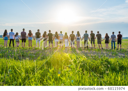 Cohesion concept. A group of friends are holding hands at sunset. Cohesion concept. A group of friends are holding hands at sunset. 68115974
