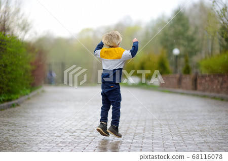 Little boy walking on rainy spring day in small town Little boy walking on rainy spring day in small town 68116078