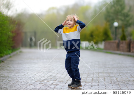 Little boy walking on rainy spring day in small town Little boy walking on rainy spring day in small town 68116079