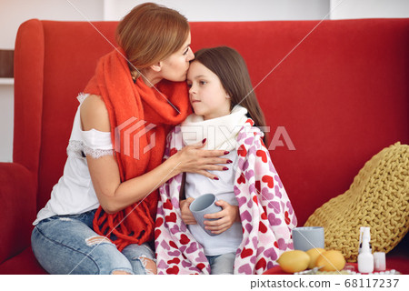 Mother gives her sick daughter hot tea Mother gives her sick daughter hot tea 68117237