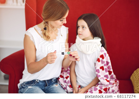 Mom measures the temperature of her ailing daughter Mom measures the temperature of her ailing daughter 68117274