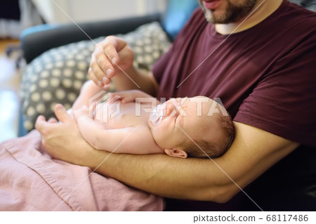 Cute newborn baby lying in arms of his father. Cute newborn baby lying in arms of his father. 68117486