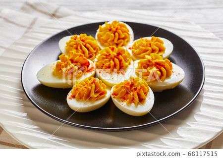 Stuffed egg halves on a black plate, close-up 68117515