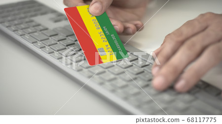 Unknown man pays online with plastic bank card with printed flag of Bolivia. Fictional numbers 68117775
