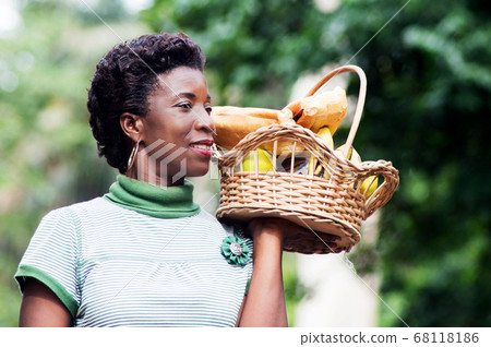 smiling young woman holding a fruit basket. 68118186