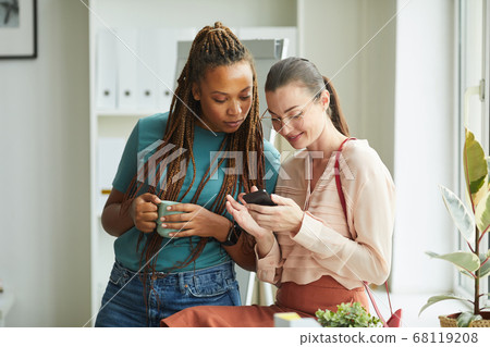 Two Women using Smartphone in Office Two Women using Smartphone in Office 68119208