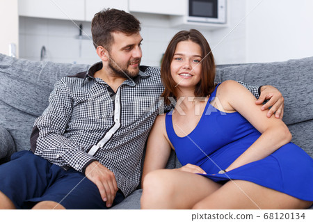 Smiling young couple sitting at sofa together at home interior 68120134