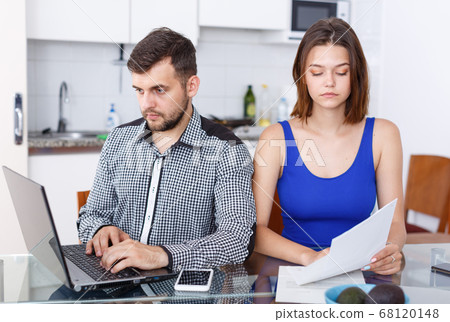 Serious young family couple with documents using laptop Serious young family couple with documents using laptop 68120148