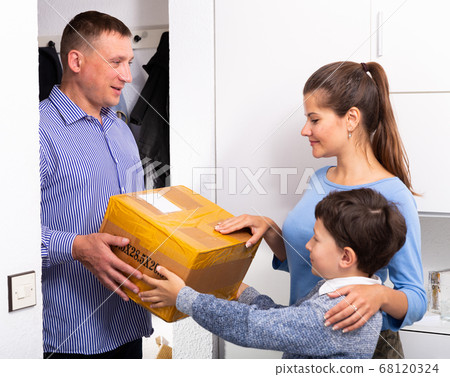 Happy family greets father with package at home Happy family greets father with package at home 68120324