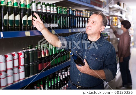 Portrait of an elderly couple buying a beer at the grocery store Portrait of an elderly couple buying a beer at the grocery store 68120326