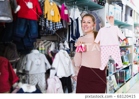 Female buyer choosing clothes for infant Female buyer choosing clothes for infant 68120415